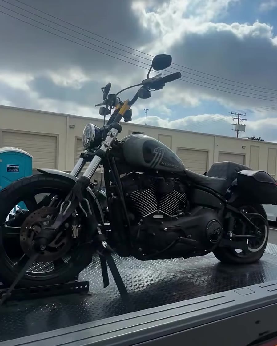 Harley Softail secured with straps on black bed