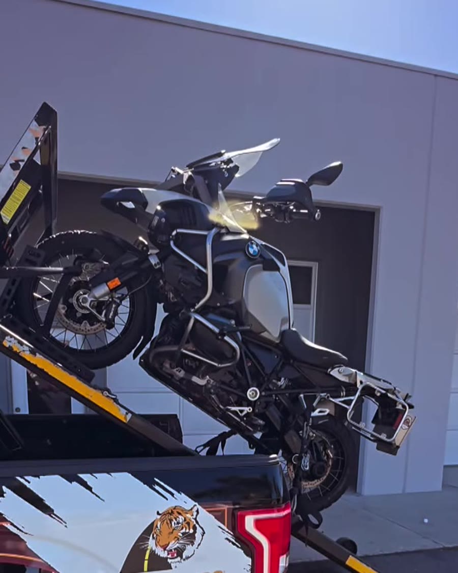 BMW adventure bike on Law Tigers black truck hydraulic lift
