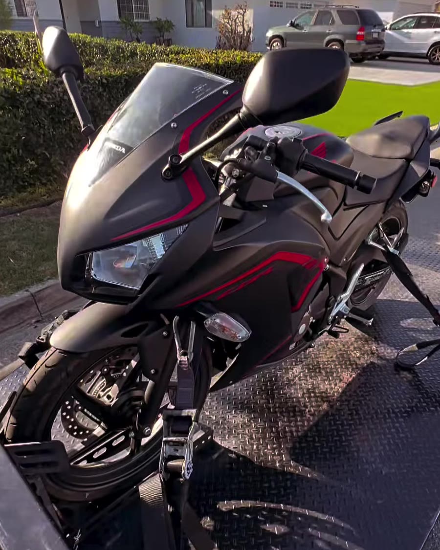 Black and red Honda sportbike strapped on black diamond-plate bed