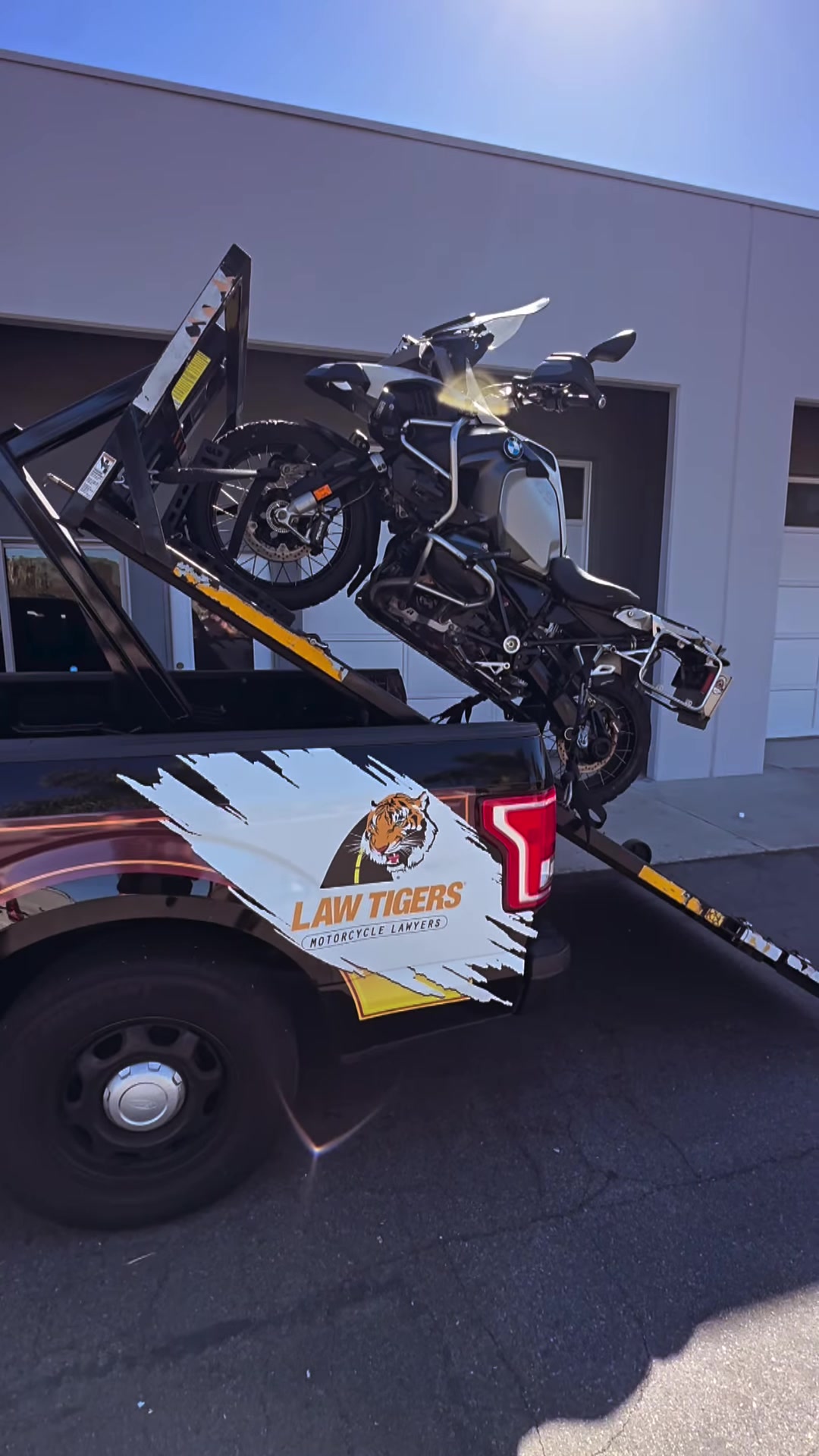 Hydraulic lift loading a motorcycle on Law Tigers black truck